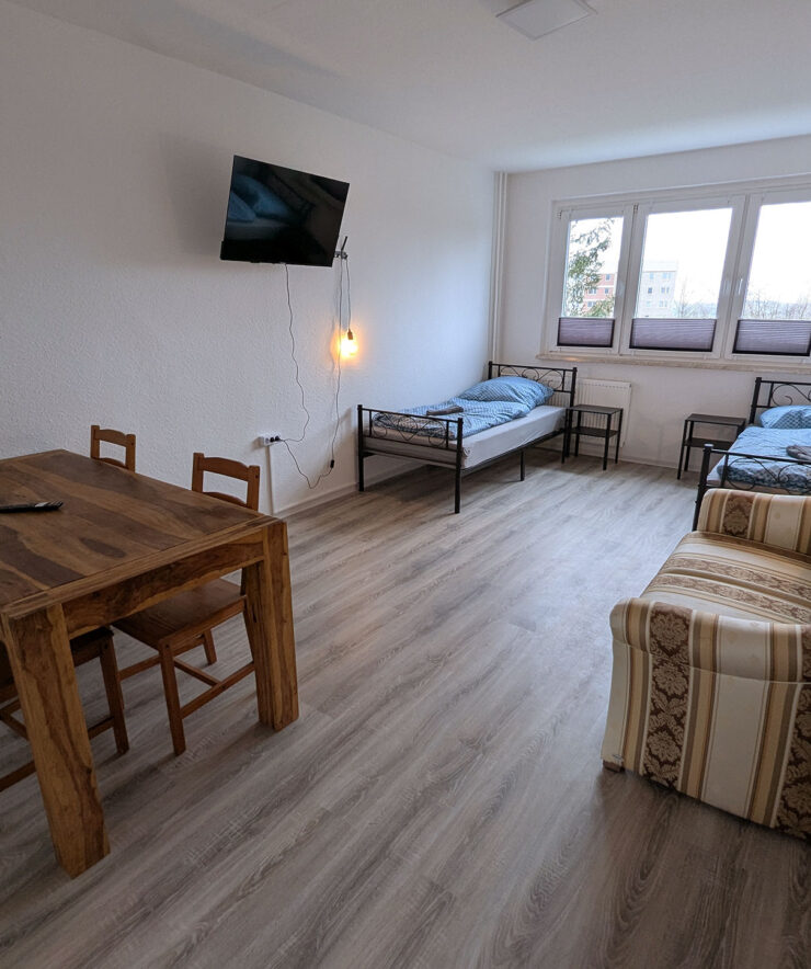 Nova: Schlafraum mit 2 Betten, Tisch, Stühlen und Sofa