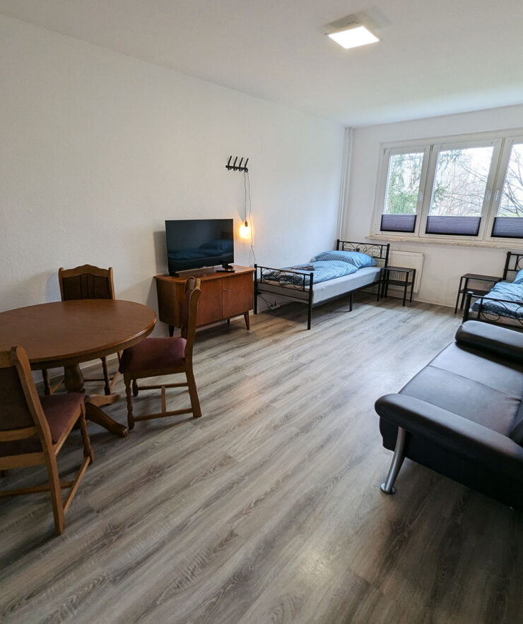 Mira: Schlafraum mit 2 Betten, Tisch, Stühlen und Sofa